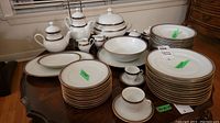 Full overview of white china pieces arranged on table, showing stacks of plates, bowls, cups, pots and serving dishes