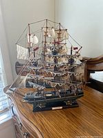 Front view of larger warship model showing details of sails, rigging, and plaque on stand