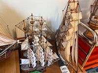 Four wooden model ships displayed together showing size and detail of sails, rigging, and flags.