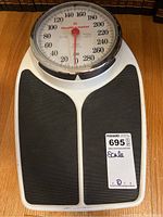 Top view of the Healthometer Big Foot scale showing the black rubber foot pads and white plastic frame with the large dial and red needle indicator.