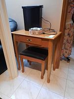 Wood table with drawer and matching stool underneath, showing full set and condition.