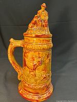 Full view of the ceramic beer stein with lid, showing the front detailed relief of a deer and overall glaze finish.