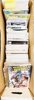 Top view of comics in cardboard box showing several bagged comics with some written dividers.