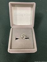 Front view of sterling silver wave ring in grey padded jewelry box with 'Sterling Silver' embossing in lid.
