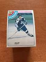 Front view of a single 1978/79 OPC hockey card featuring George Ferguson of the Penguins in his team uniform, holding a hockey stick.