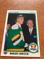 Front of Derian Hatcher 1990/91 Upper Deck rookie hockey card showing player in Minnesota North Stars jersey and hat.