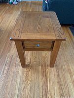 Front view of the hardwood end table showing natural wood grain surface, four legs, and tabletop panel design.