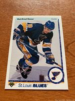 Front of Rod Brind'Amour rookie card showing player in St. Louis Blues blue uniform, skating with hockey stick.