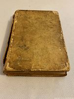 Front cover of antique book showing worn brown leather binding with scuffs and edge wear.
