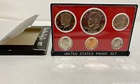 Front view of the 1977-S US coin proof set displaying all six coins in plastic holder with red background and black base labeled 'UNITED STATES PROOF SET'.