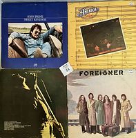 Four rock LP records with album covers: John Prine - Sweet Revenge, America - Live, Rod Stewart - The Rod Stewart Album, Foreigner - Foreigner.