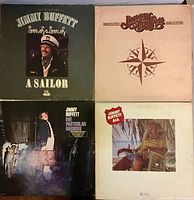 Four front album covers of Jimmy Buffett records shown: Son of a Son of a Sailor, Changes in Latitudes Changes in Attitudes, One Particular Harbour, and A1A.