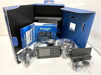 Sirius XM Satellite Radio receiver and accessories laid out outside original packaging box showing user guide, power cables, and mounting bracket.