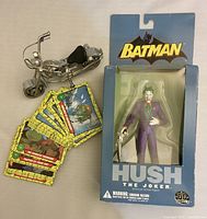 Front view of Joker action figure boxed with miniature motorcycle and fan of TMNT cards showing colorful graphics