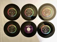 Six 45 RPM Nat King Cole vinyl records laid out flat, showing top surfaces and labels