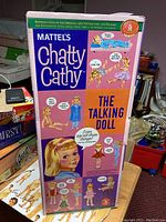 Front of Chatty Cathy reproduction doll box showing colorful vintage graphic design and doll images.