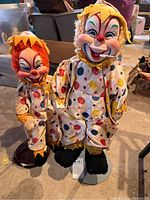 Photo showing both clown dolls standing on round bases with colorful polka dot costumes and yellow felt trim.