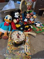 Overview of all Disney collectibles including Mickey Mouse telephones, Donald Duck plush, Mickey clock, puzzles, mirror and additional figurines.
