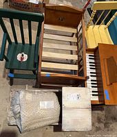 Top view of entire set showing positioning of green high chair, rocking bed, crib, piano and yellow chair with a blanket or textile item included.