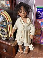 Full front view of the doll standing next to a vintage jukebox and a Mattel doll box, showing clothing and overall appearance