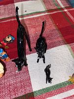 Black cat figurines featured in different sizes and poses alongside parts of other figurines.