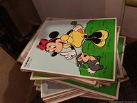 Stack of vintage children's board puzzles with Minnie Mouse cover puzzle on top, shows puzzle pieces intact and stacked puzzle boards below.