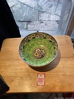 Top-down view of antique Maling pottery bowl showing decorative floral pattern in center and green scale texture inside bowl.