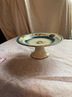 Side angle showing the full pedestal cake stand with floral design and gold accent on the stand base.