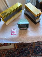 Green plastic Argyus PreViewer slide viewer placed on a white fabric surface alongside two yellow plastic slide boxes containing 35mm slides.