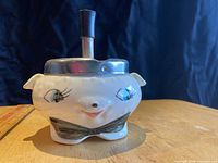 Front view of the ceramic spinner ashtray showing character face with painted eyes, mouth, and bow tie.
