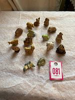 Photo showing entire set of 16 small vintage Wade tea animal figurines arranged on a fabric surface, variety of animal types and colors visible.
