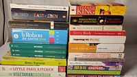Stacked books showing the variety of titles and genres included in the lot.