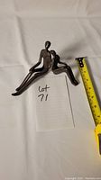 Top view of the bronze sculpture showing two abstract human figures sitting, with a tape measure for scale and a note indicating lot number.