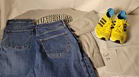 Gray University of Waterloo hoodie, two blue denim jeans, and Adidas yellow/black running shoes arranged on a surface with Lot 54 tag visible.