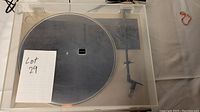 Full view of turntable with clear dust cover showing the platter and tonearm.