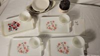 Overview photo showing the arrangement of the plates with floral patterns, cups, au gratin dishes, and crock jar spread out on the table.