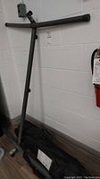 Metal hammock stand frame leaning on wall with carry bag beneath