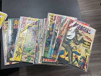 Front view of multiple Avengers comics in sleeves on black table