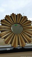 Front view of round mirror with wood frame resembling sunburst pattern showing details of the wood segments and mirror reflection.