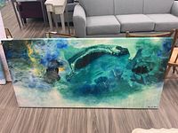 Full view of the large horizontal abstract print showing swirling blue and green tones on a lacquered surface.