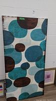Full view of the abstract canvas print showing blue, teal, and brown rounded organic shapes on light background.