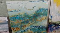Full frontal shot of the square abstract print on canvas showing blue, teal, gold, rust, and white color scheme with textured appearance.