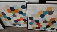 Photo showing two framed geometric hexagon pattern prints side by side with colorful hexagons and a distressed white background.