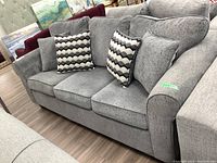 Front three-quarter view of gray sofa showing seat cushions, rolled arms and accent pillows