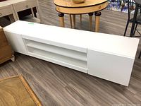 Full front view of white TV bench showing central shelving and side cabinets