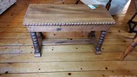 Full view of wooden bench showing rectangular seat with rounded decorative edge and four spiral-turned legs.