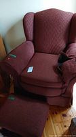 Wingback red upholstered side chair and matching ottoman stool shown together with visible upholstery texture and condition.