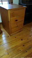 Side view of wooden filing cabinet showing two drawers and brass handles, scratches on wood visible.