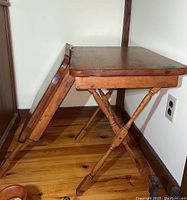 Side view of one carved wood folding table showing folding mechanism and leg details.