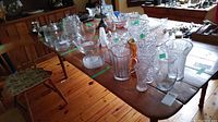 Vintage maple wood harvest table with various glassware items placed on top, showcasing table surface and drop-down sides.